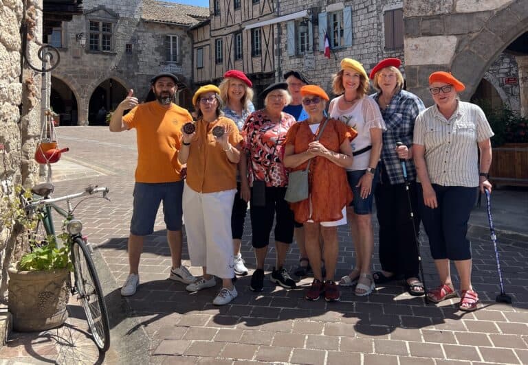 Group of diverse tourists wearing colorful hats in a historic European town square.