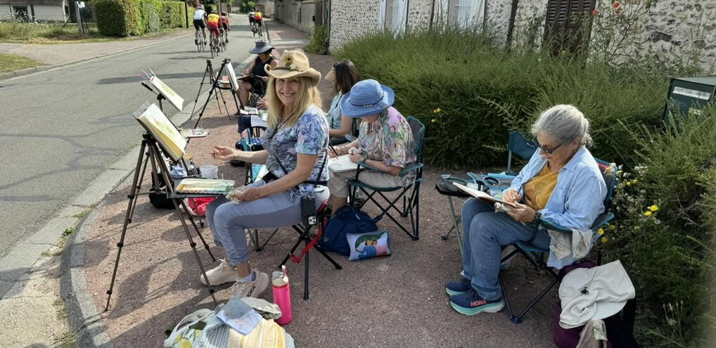 Group of people painting outdoors on a sunny day in a park setting.